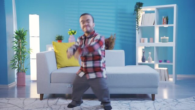 Young man with dwarfism dancing excitedly and pleasantly having fun at home.
Disabled dwarf young man at home alone having fun, dancing wildly and in good spirits.
