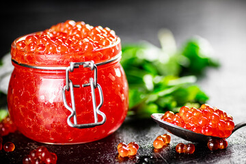 Red caviar in a glass jar with parsley. 