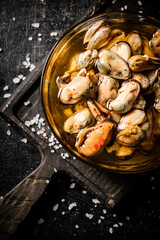 Bowl with pickled mussels on a cutting board. Top view. 