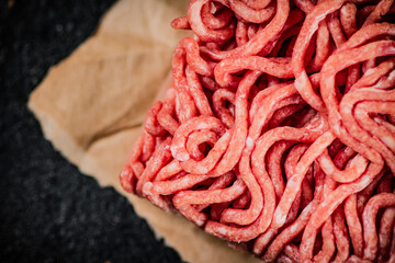 Raw minced meat on paper on the table. 