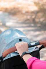 Mano de una mujer joven llevando una carriola maternidad fitness por la calle imagen en formato vertical 
