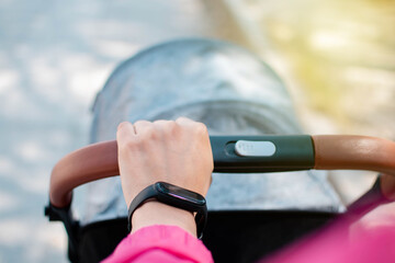 Mano de una mujer joven manejando una carreola en la calle con un smartwatch