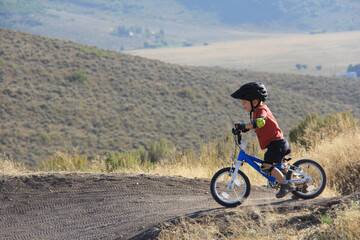 Fototapeta premium little boy biking in the mountains
