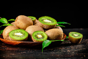 Fresh kiwi with leaves on a wooden plate. 