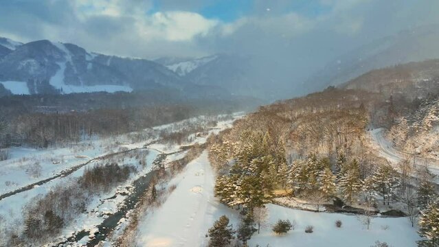 winter wonderland in snowy mountains in Japan, Hakuba valley, frosty weather with below freezing temperatures, aerial view of frozen river
