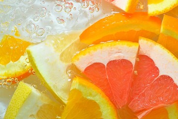 Close-up view of the grapefruit, orange fruit and honey pomelo slices in water background. Texture...