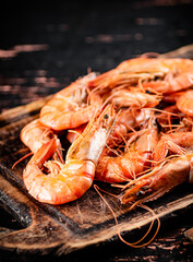 Cooked shrimp on a wooden cutting board. 