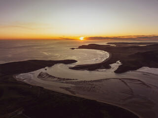 Stunning aerial drone evening sunset view of Porpoise Bay and Curio Bay near Waikawa, part of the Catlins Coast, an area in the southeastern corner of New Zealand's South Island, Southland region.