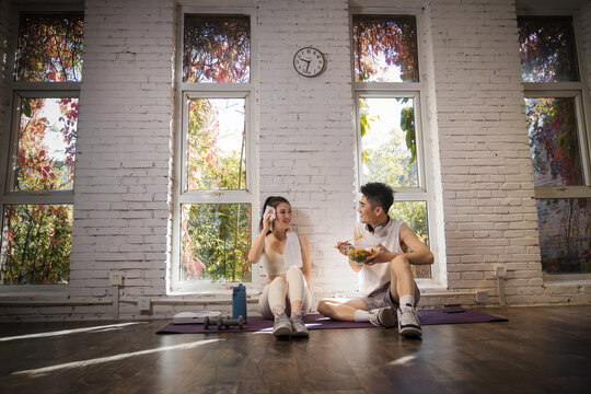 Young couple sitting on the ground to rest after workout