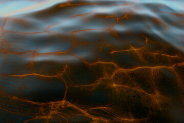 Abstract photo of the reflection of light from the surface of the movement of the water waves of the river from the sky in yellow and gold tones. The background is magical.