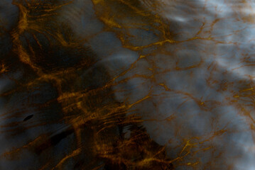 Abstract photo of the reflection of light from the surface of the movement of the waves of the transparent water of the river from the sky in gray-yellow tones. Background.