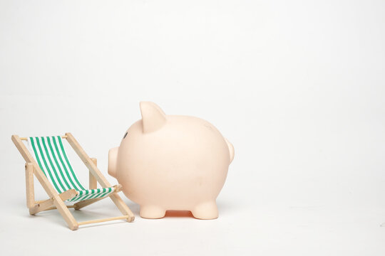 A picture of miniature folding beach chair and with piggy bank on white background