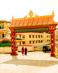 Two Tibetan monks walking towards monastery gate.