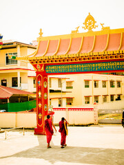 Two Tibetan monks walking towards monastery gate.