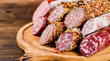 Different types of salami sausage on a wooden cutting board. 