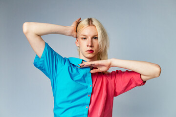 Studio photo of a man with make up on one half of face and rose and blue shirt