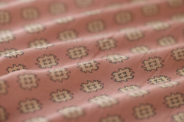 Wavy pink and white fabric with abstract ornament as background.