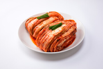Korean kimchi. Korean traditional cabbage kimchi on a white plate. White background, closeup.