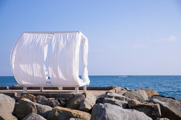 Scenic view empty white beach wooden canopies cabanas with white curtain blowing by wind against sea or ocean san seaside. Luxury sunbed for spa and leisure vacation.relaxation and tranquility
