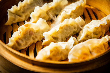 Dumplings gyoza in a bamboo steamer with hot steam. 