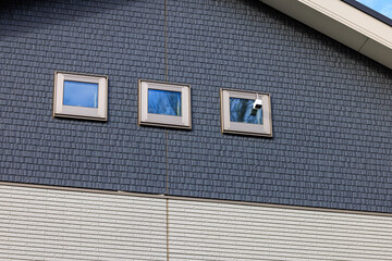 住宅の2階の小窓に取り付けられた防犯カメラ