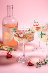 refreshing fruit cocktail. Glasses with cold pink champagne or punch with wine strawberries on pink background. place for text
