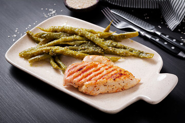 Chicken fillet cooked on a grill and garnish of green beans.