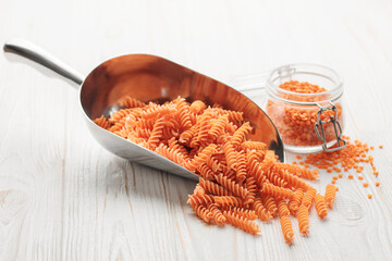 Fusilli red lentil pasta on a wooden background.