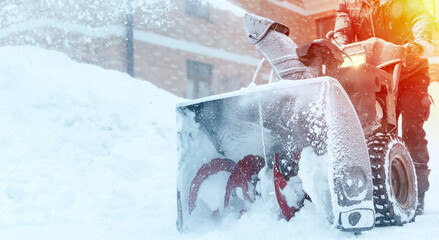 a janitor on a snowplow removes snow in the courtyard of a residential building in