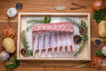 Australian lamb rack cutlets or Raw Frenched Rack 8 Ribs with potato, Rosemary on wooden plate.
