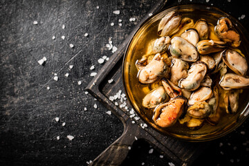 Bowl with pickled mussels on a cutting board. Top view. 