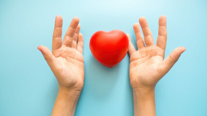 child's hands and a small toy heart on a blue background. concept of child health, medical examination, world health day, organ and blood donation