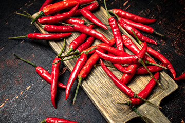 Red chili pepper pods on a cutting board.