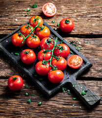 Fresh tomatoes on a branch on a cutting board. 