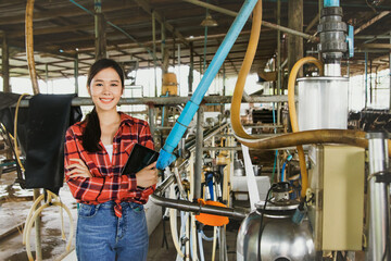 Portrait Asian female health worker standing with hands crossed check the cleanliness of the cow farm milking machine in the countryside. that are hygienic and safe according to standards.