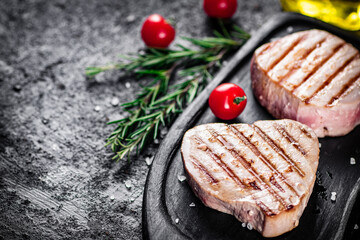 Grilled tuna on a tray with tomatoes and rosemary. 