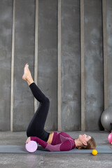 A woman performs myofascial unloading of the buttocks, using rolling on a yoga mat. Myofascial release, MFR.