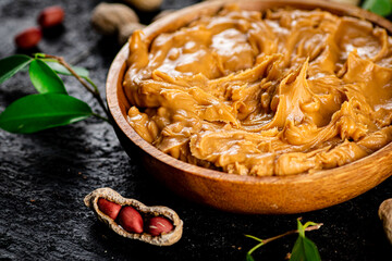 Peanut butter in a wooden plate on the table. 