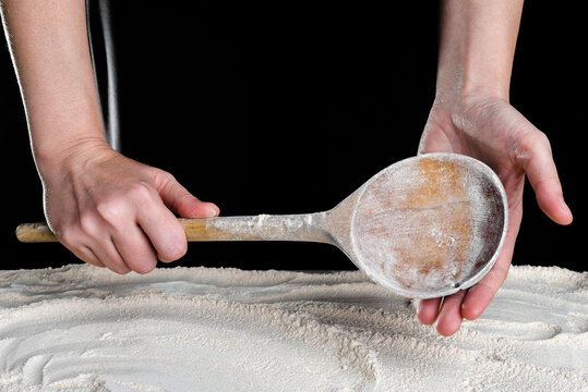 Baker with wooden spoon above flour. Baking concept.