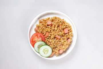Nasi Goreng Sosis is Fried Rice with Sausages garnished with fresh cucumber and tomatoes slices.
