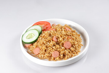 Nasi Goreng Sosis is Fried Rice with Sausages garnished with fresh cucumber and tomatoes slices.