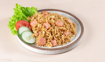 Nasi Goreng Sosis is Fried Rice with Sausages garnished with fresh cucumber and tomatoes slices.