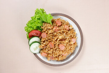 Nasi Goreng Sosis is Fried Rice with Sausages garnished with fresh cucumber and tomatoes slices.