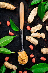 A spoonful of peanut butter on a table with leaves.
