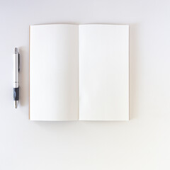 Open white blank on white background with pen. Travel notebook or sketchbook.