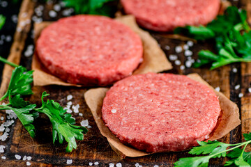 Raw burger on a cutting board with parsley and salt. 