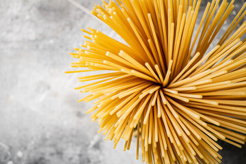 A bundle of spaghetti dry tied with a rope stands on the table. 