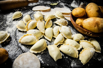 Raw potato dumplings on a stone tray with rolling pin and flour. 