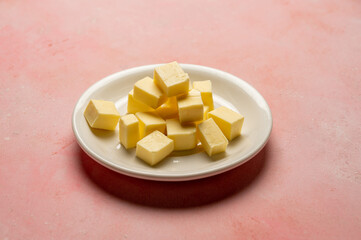 Butter cubes sliced, dairy product, cooking ingredient. Pink background