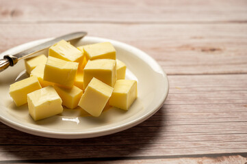 Butter cubes sliced, dairy product, cooking ingredient. Wooden background, copy space